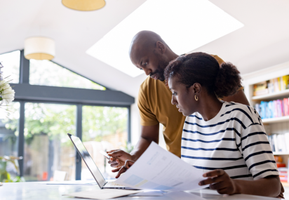 Couple checking information on paper and laptop